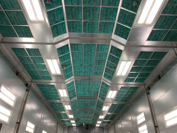 Long downdraft paint booth with fresh green ceiling filters and bright lights after a filter change